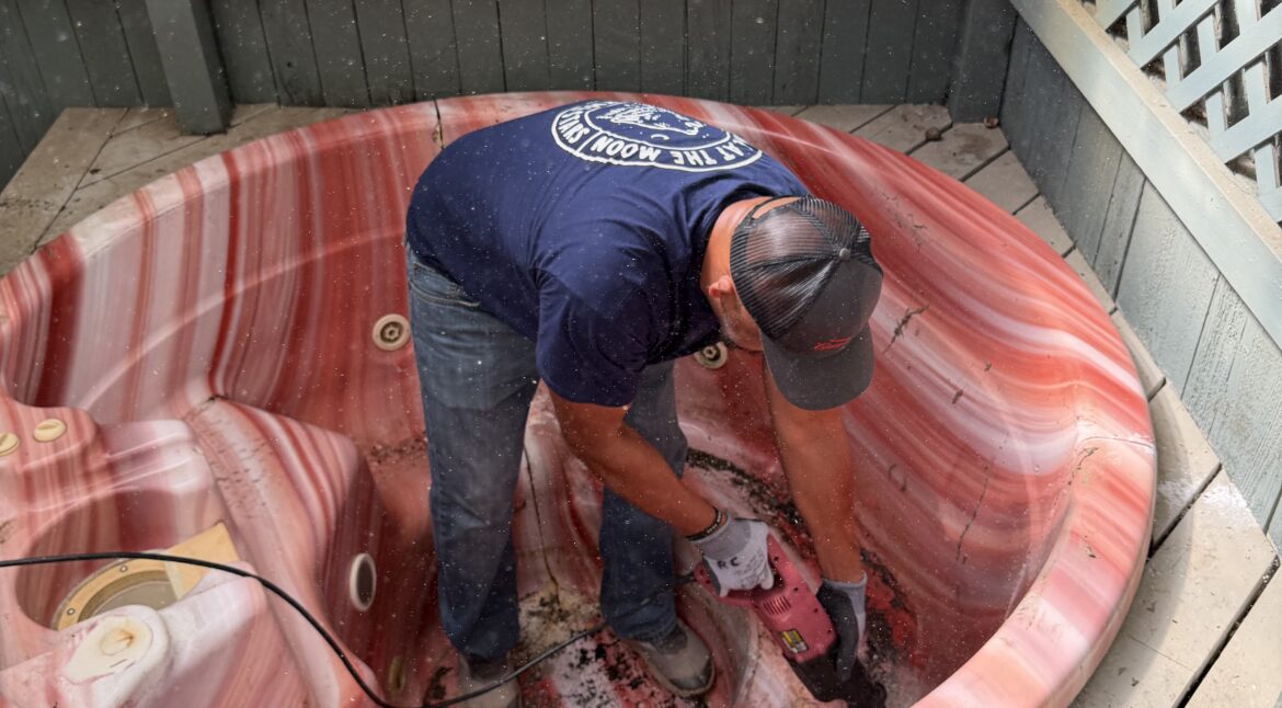 EZ Junk & Hauling crew member cutting a hot tub into quarters from the inside to protect the surrounding deck