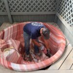 EZ Junk & Hauling crew member cutting a hot tub into quarters from the inside to protect the surrounding deck