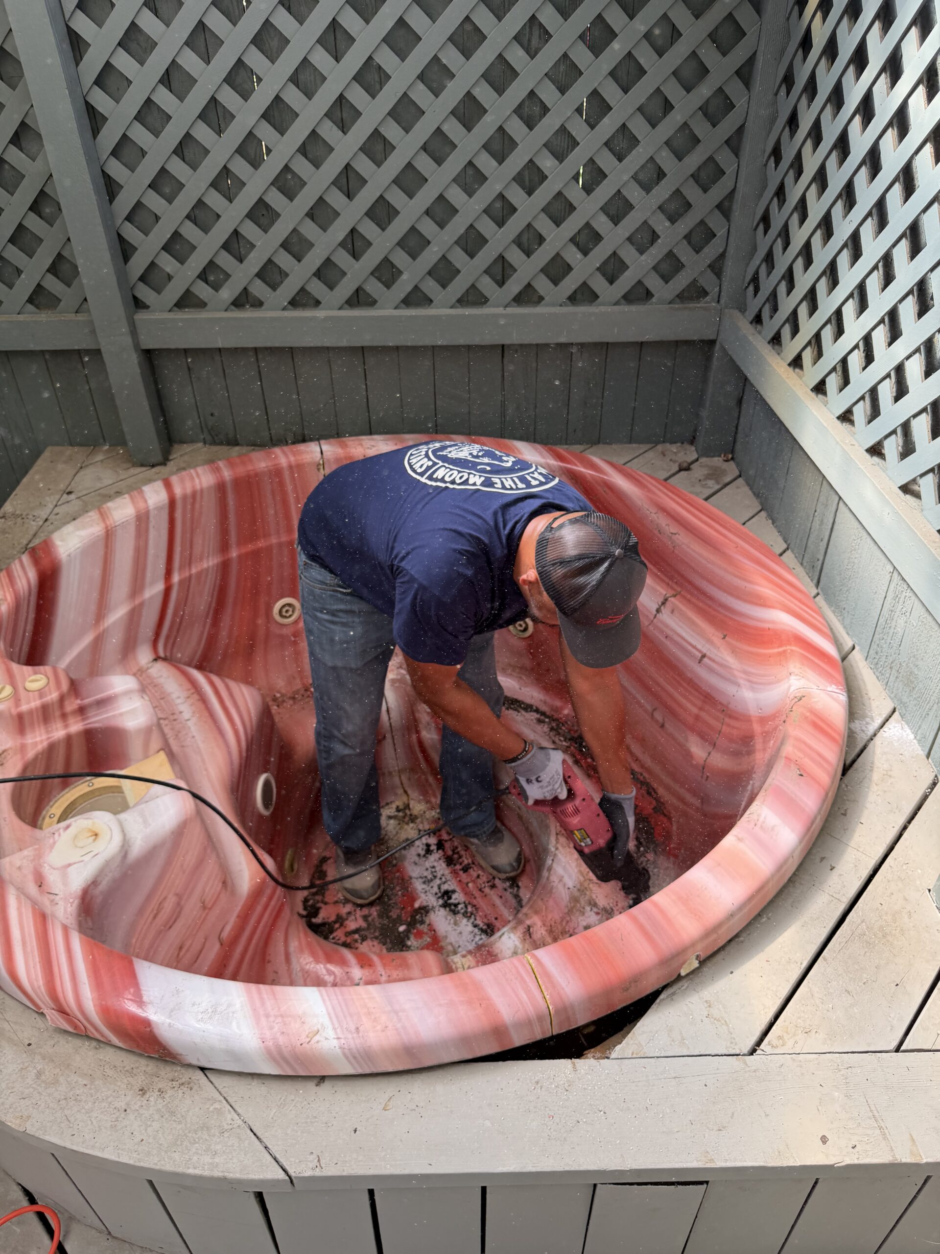 EZ Junk & Hauling crew member cutting a hot tub into quarters from the inside to protect the surrounding deck